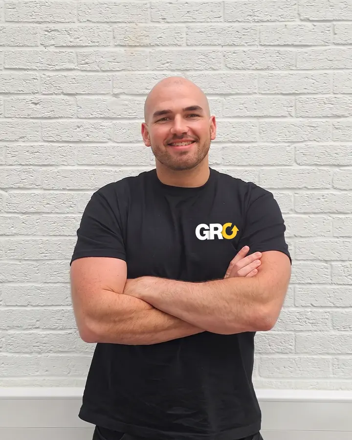 John Parnell, founder of GRO, arms folded in a GRO t-shirt against a white brick wall